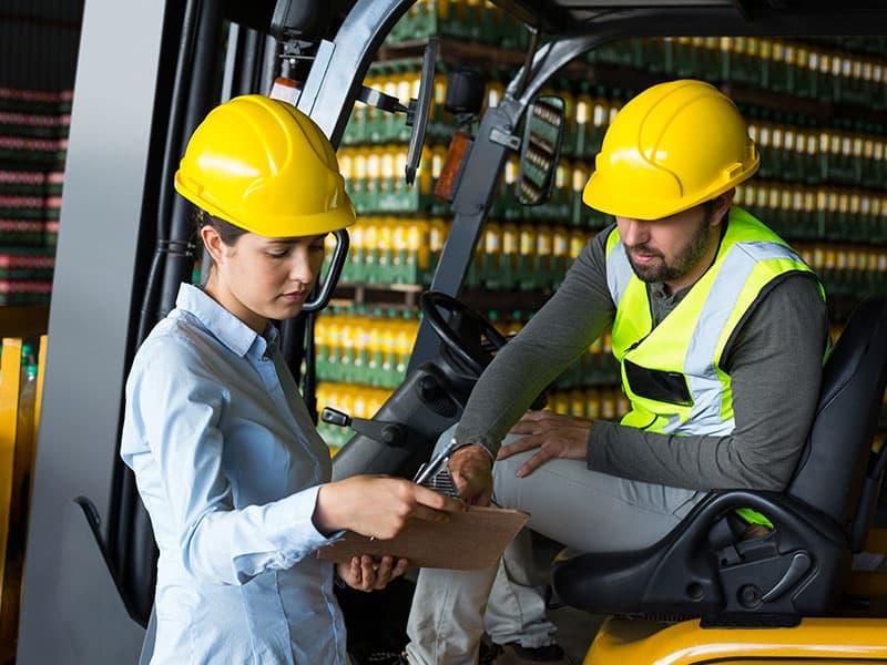 Brennan Blog Forklift Maintenance Tips Factory Workers Checking Record On Clipboard In Warehouse | Schelkovskiy &Co Brennan Equipment Services