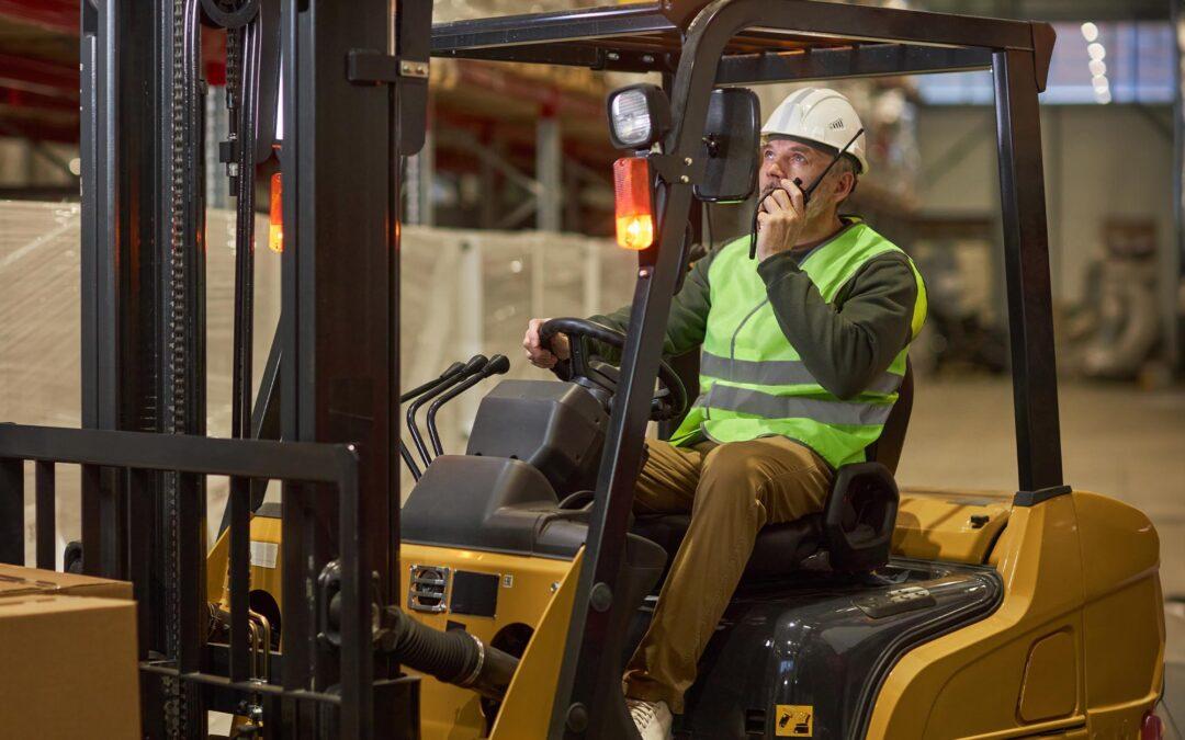 Side View Of A Man Talking On A Walkie Talkie While Sitting In A Forklift | Schelkovskiy &Co Brennan Equipment Services